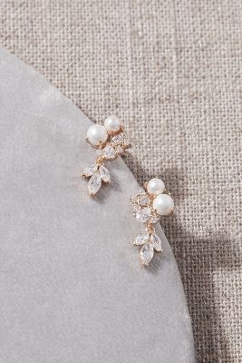 a pair of pearl and crystal earrings on top of a gray stone plated surface