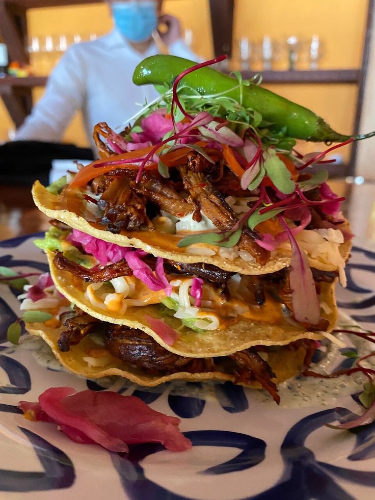 three tacos stacked on top of each other with toppings and garnishes