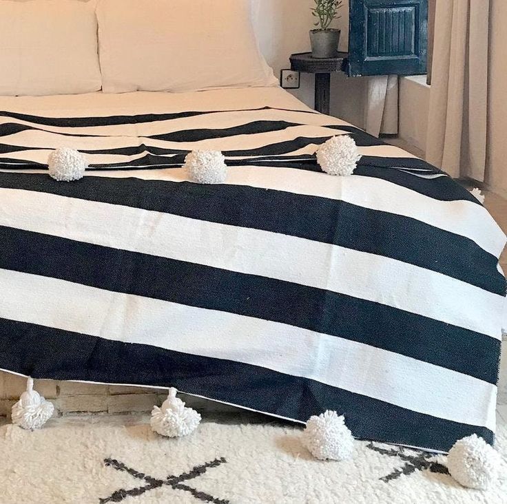 a black and white striped bed spread with pom poms on the bottom edge