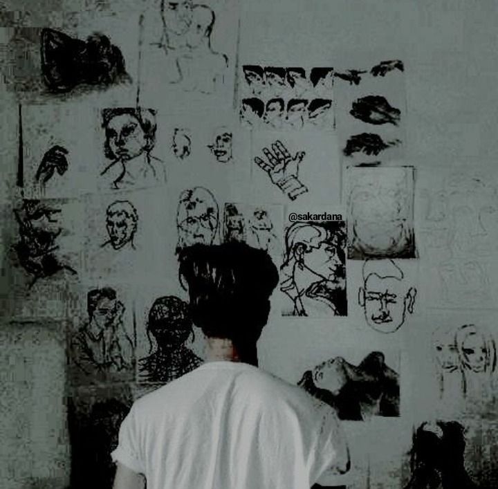 a person standing in front of a wall with drawings on it and the back of his head