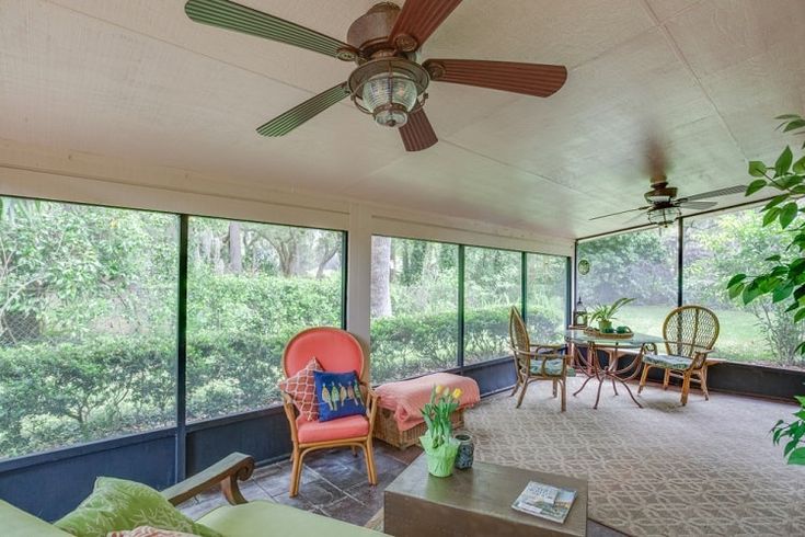 a living room filled with lots of furniture next to a large glass window covered wall