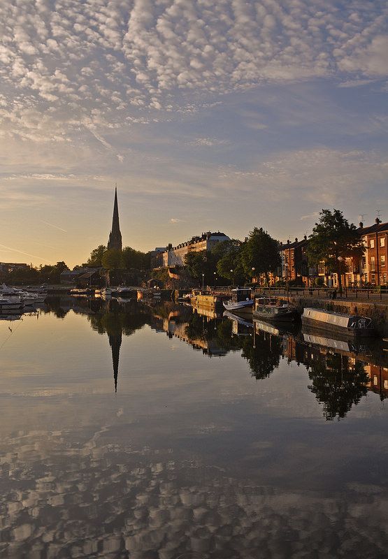 the water is calm and clear as it sits in front of some buildings on the other side