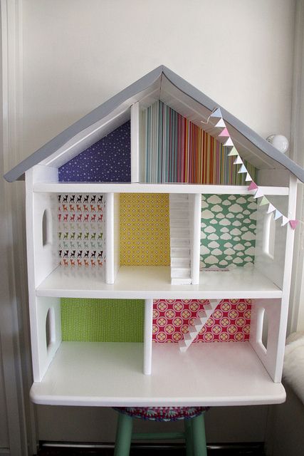 a doll house made out of several different types of fabrics and fabric strips, sitting on a stool in front of a white wall