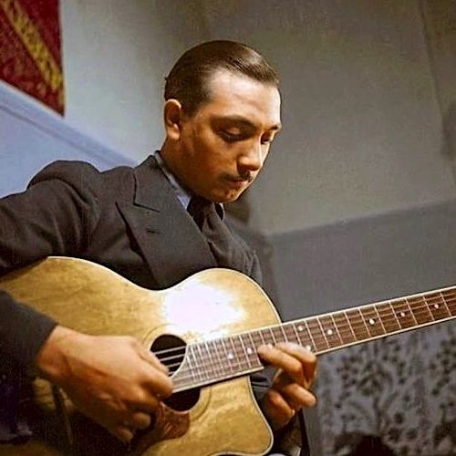 a man playing an acoustic guitar while sitting down