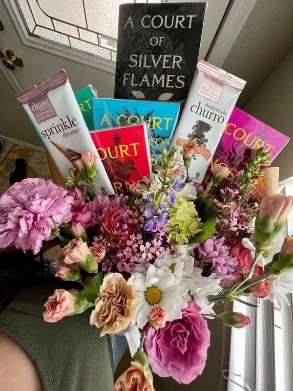 a vase filled with lots of different types of flowers and books on top of a table