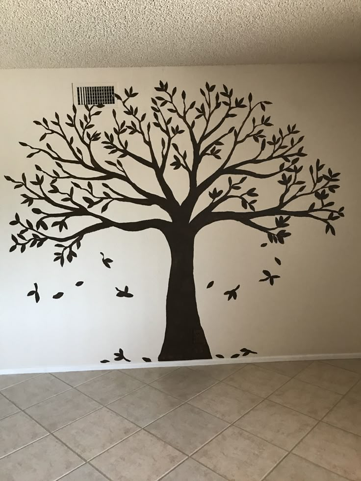 a tree with leaves and birds painted on the wall in a room that has tile flooring