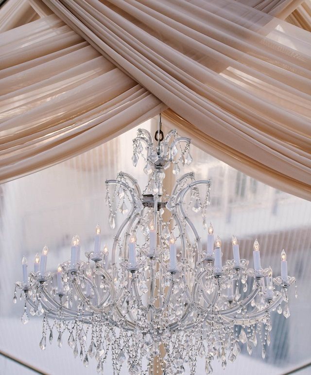 a crystal chandelier hanging from the ceiling in a room with sheer drapes