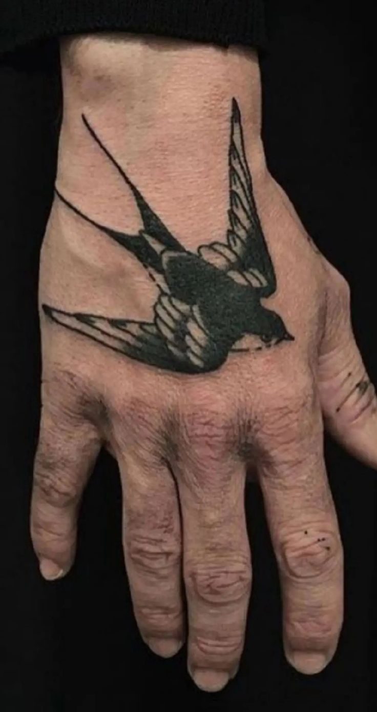 a person's hand with a bird tattoo on it