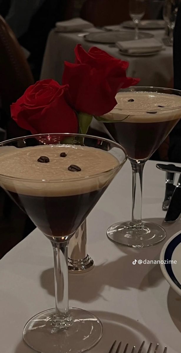 two glasses filled with chocolate martinis on top of a white table covered in plates and silverware