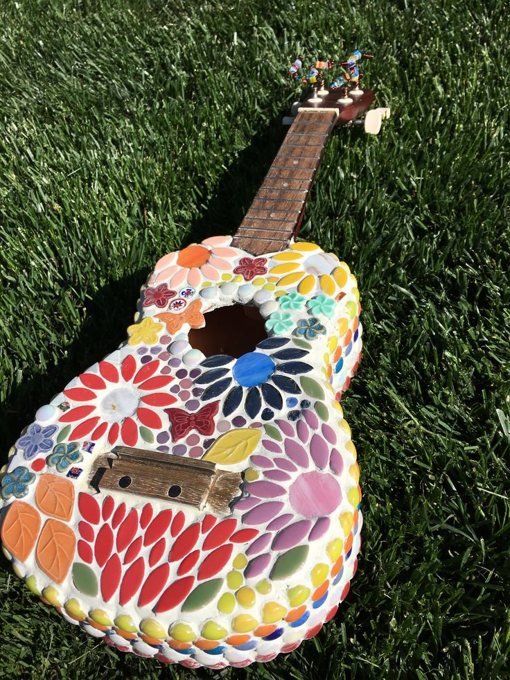 a colorful guitar sitting in the grass