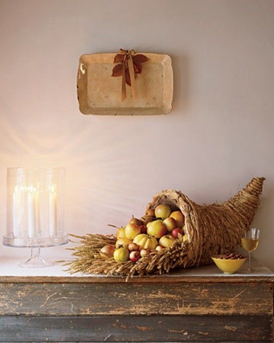 an arrangement of fruit and candles on a mantle