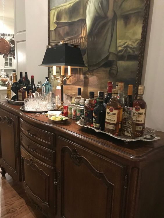 a bar with liquor bottles and glasses on top of it in front of a painting