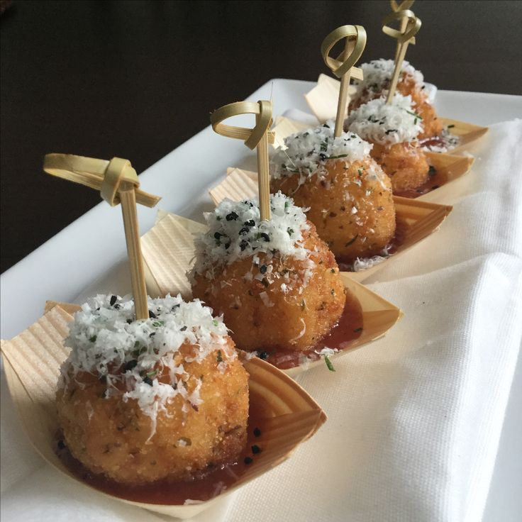 four small pastries are lined up on trays with tiny candles sticking out of them