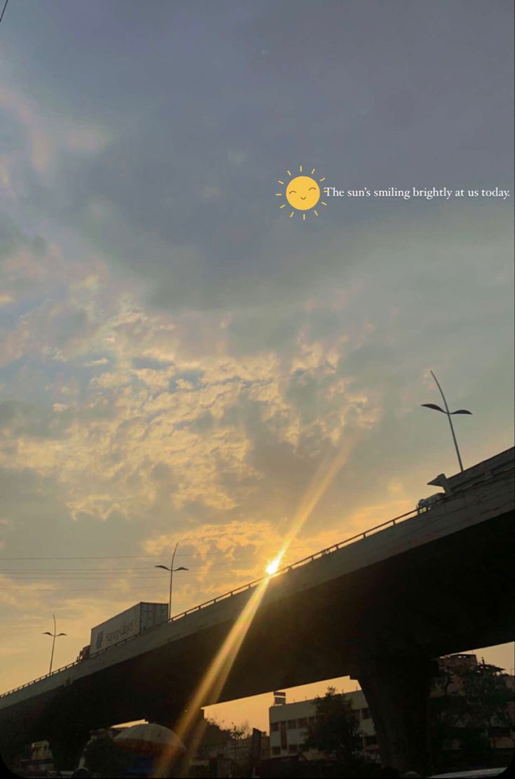 the sun is setting behind a bridge and cars are driving on the road in front of it