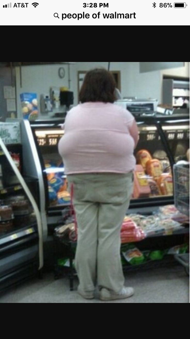 a woman standing in front of a display case at a grocery store with her back to the camera