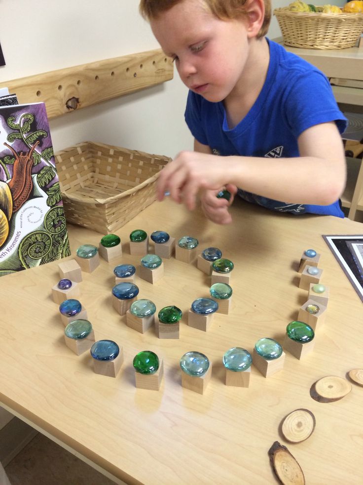 a young boy playing with wooden blocks and magnets on a table in front of a book