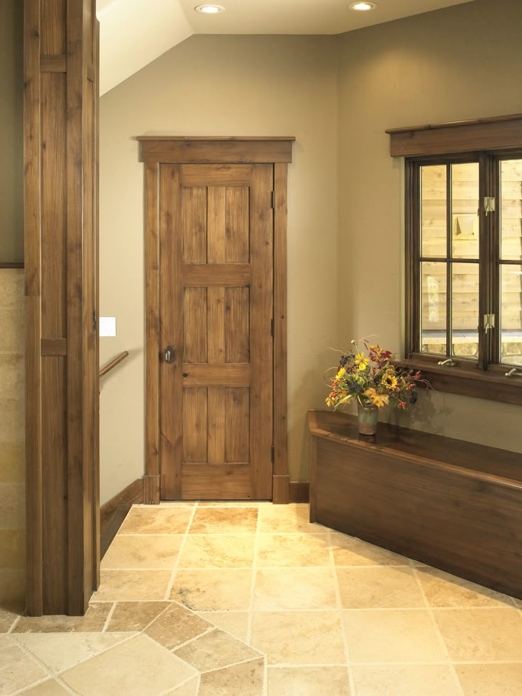 an empty room with a wooden door and window sill in the corner, next to a tiled floor