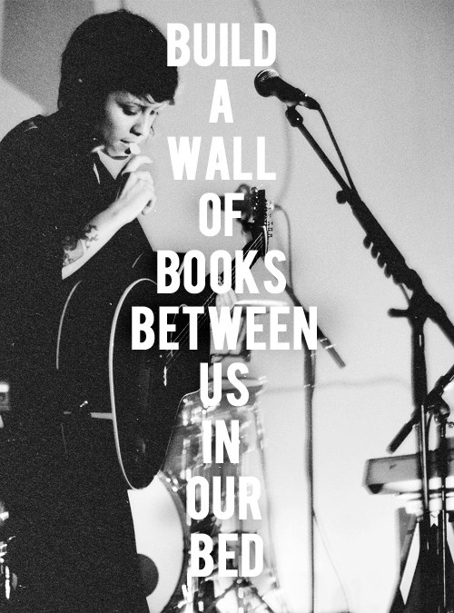 a black and white photo with the words build a wall of books between us in our bed