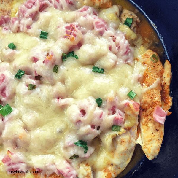 a pizza topped with meat and cheese on top of a blue plate next to green onions