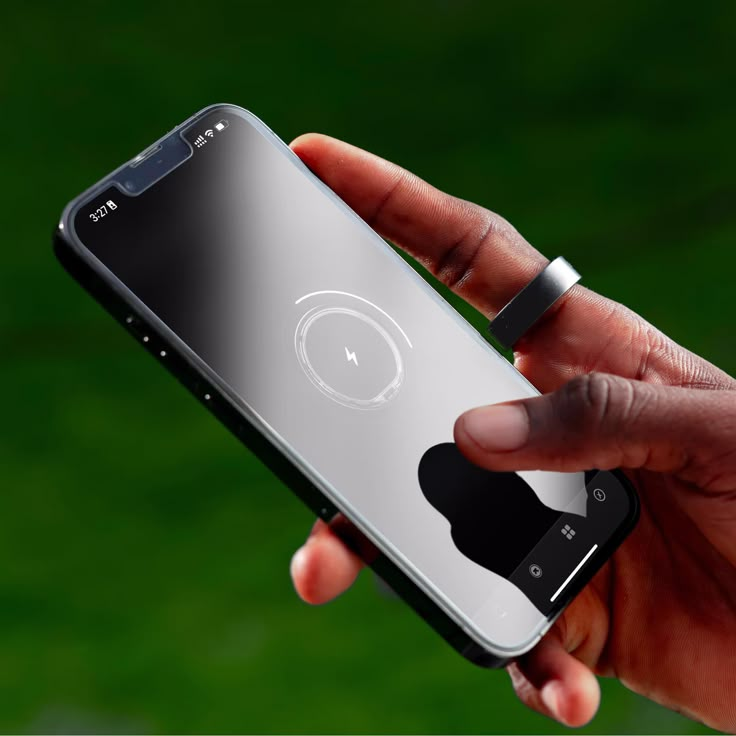 a hand holding an iphone in front of a green background with the back facing up