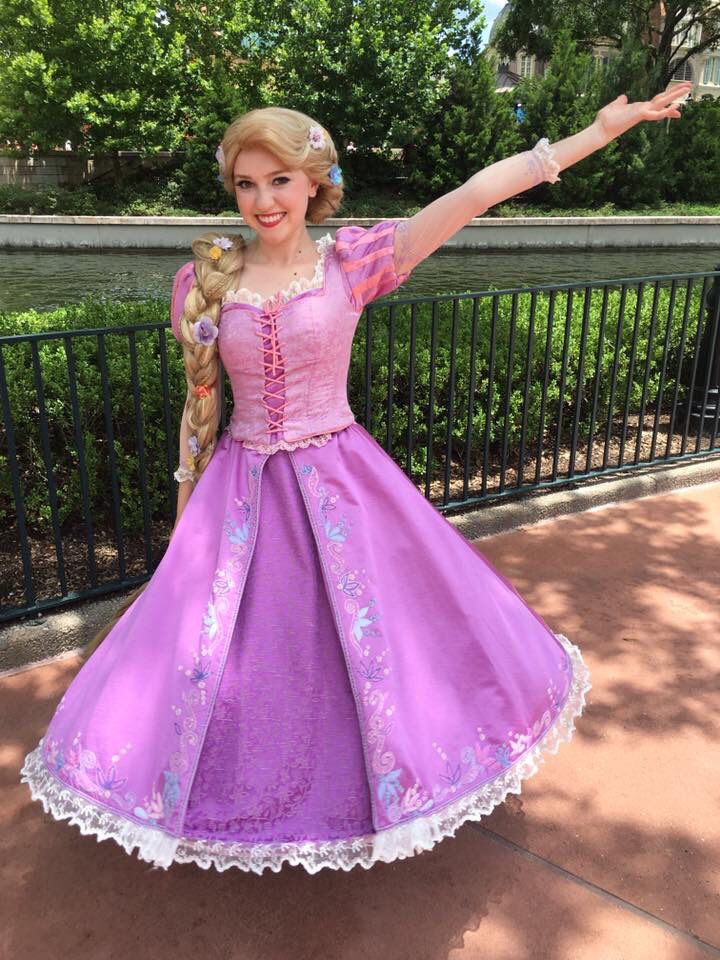 a woman in a purple dress is posing for the camera with her arms outstretched out