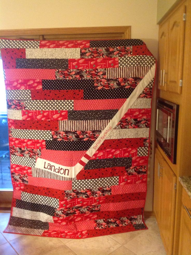 a red and black quilt hanging from the side of a kitchen counter next to a microwave