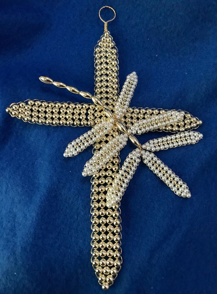 an ornament made out of beads on a blue cloth with a gold chain attached to it