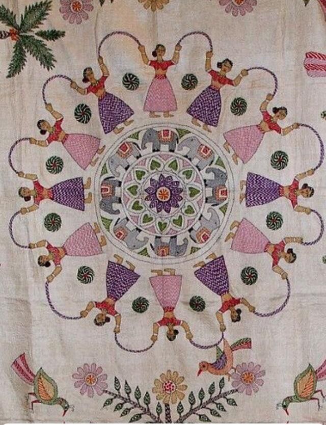 an embroidered cloth with dancers on it and flowers around the edges, is displayed in front of a white background