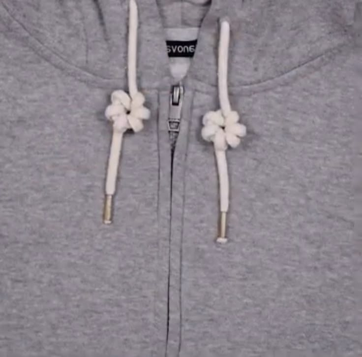 a grey hoodie with white flowers on the front and side zippers that are attached to it