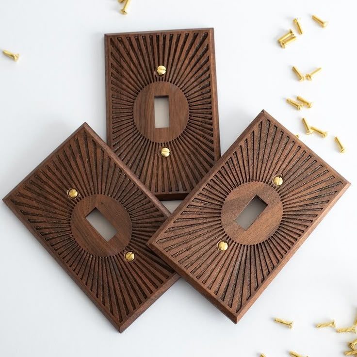 three decorative wooden pieces with holes in the middle and gold studs around them on a white surface