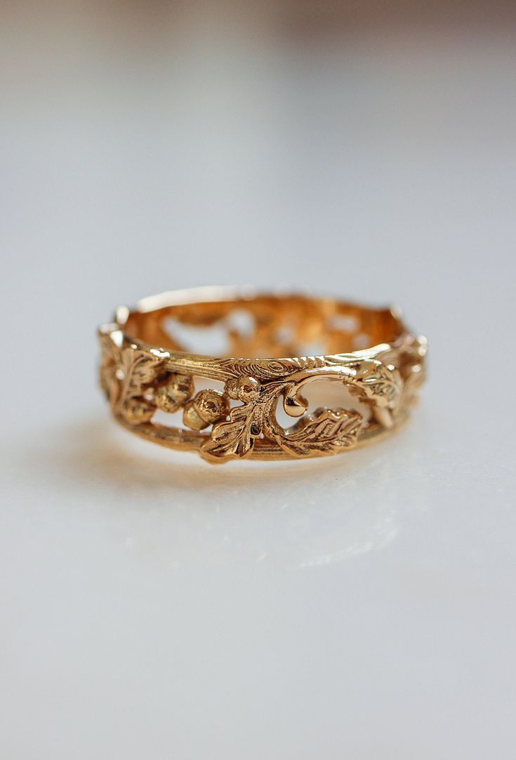 a gold ring with filigrees and leaves on the inside, sitting on a white surface