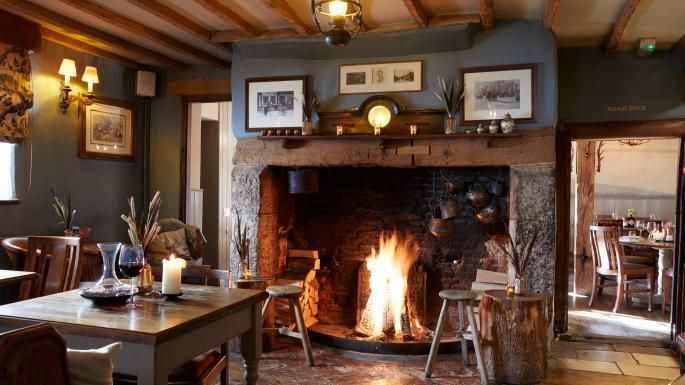 a fire place in the middle of a room with tables and chairs around it,