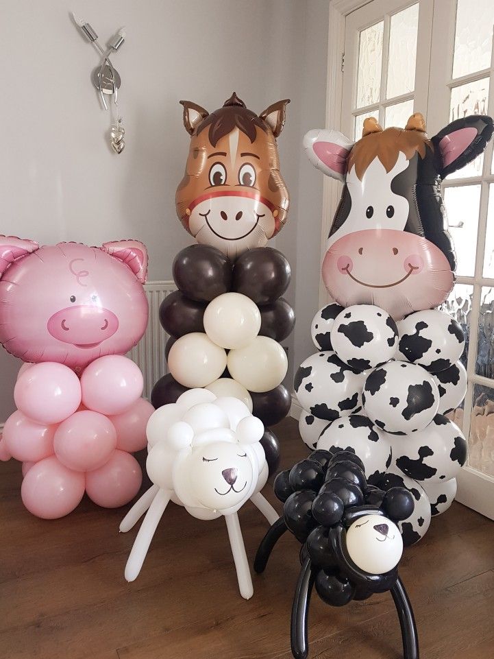 three inflatable farm animals and one balloon animal sitting on a chair with balloons attached to it