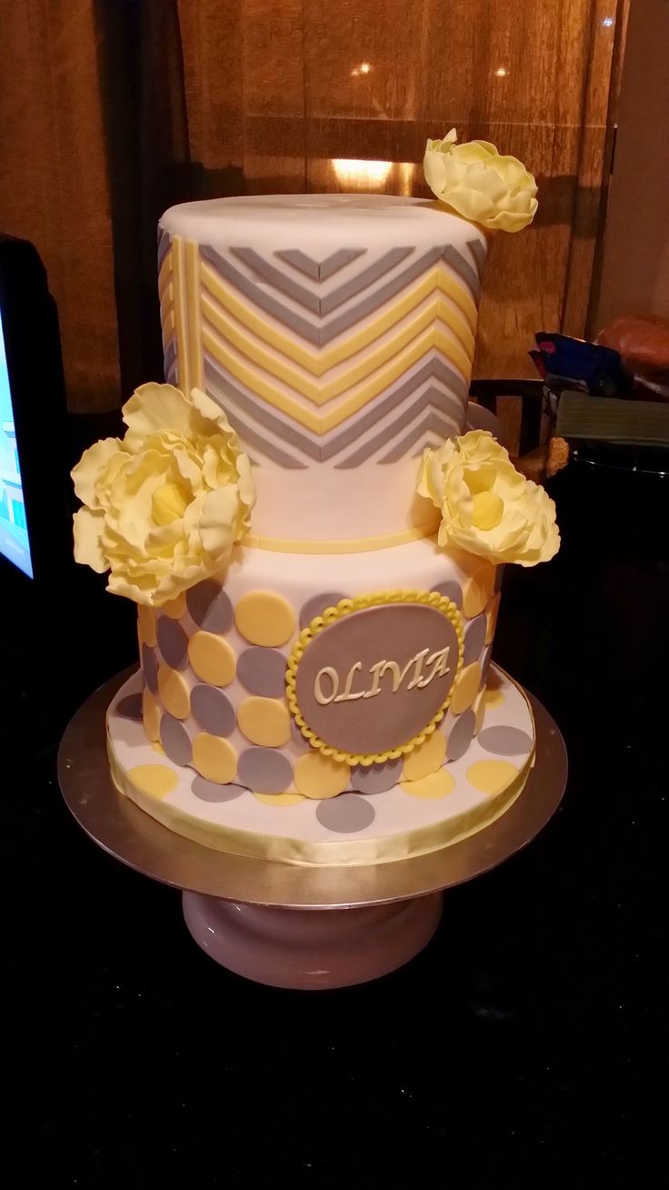 a three tiered cake with yellow flowers on the top and purple polka dot design