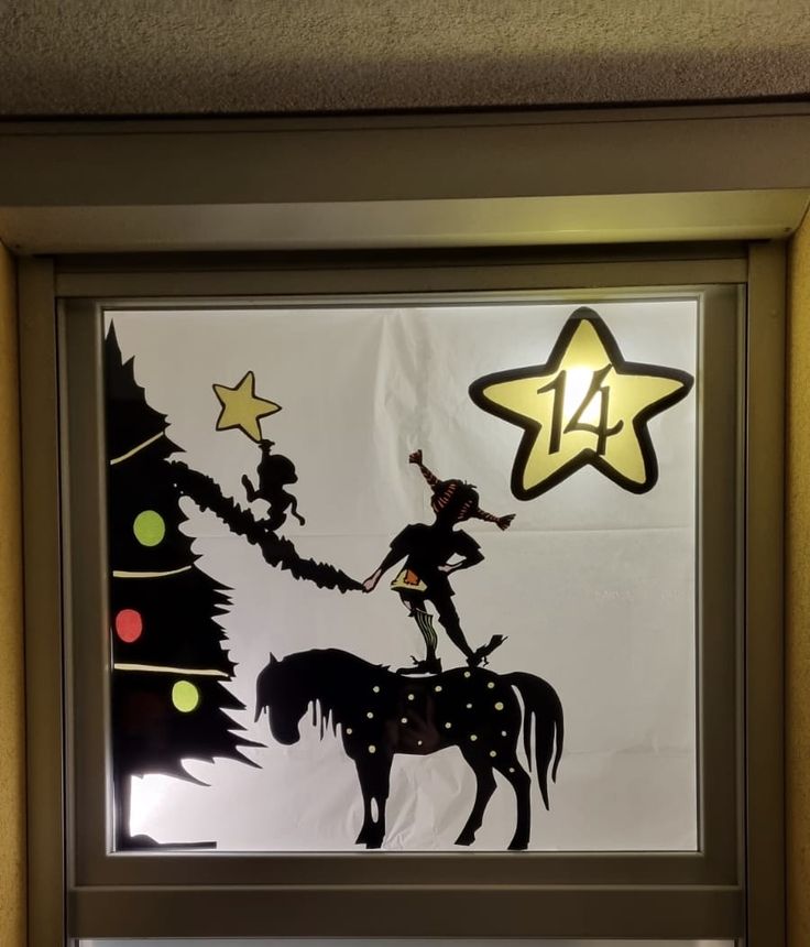 a window with a silhouette of a girl on a horse next to a christmas tree