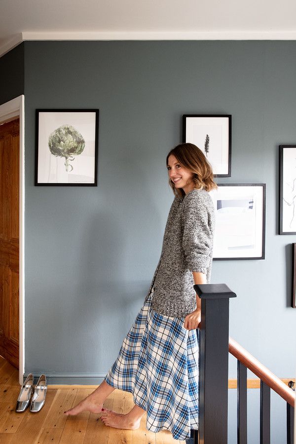 a woman standing on top of a wooden stair case next to a wall with pictures