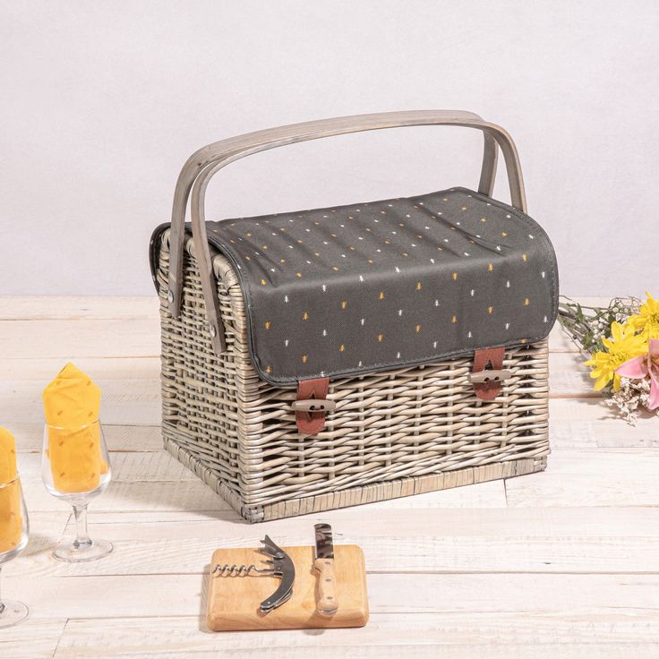 a wicker picnic basket with flowers and candles on the side, next to it