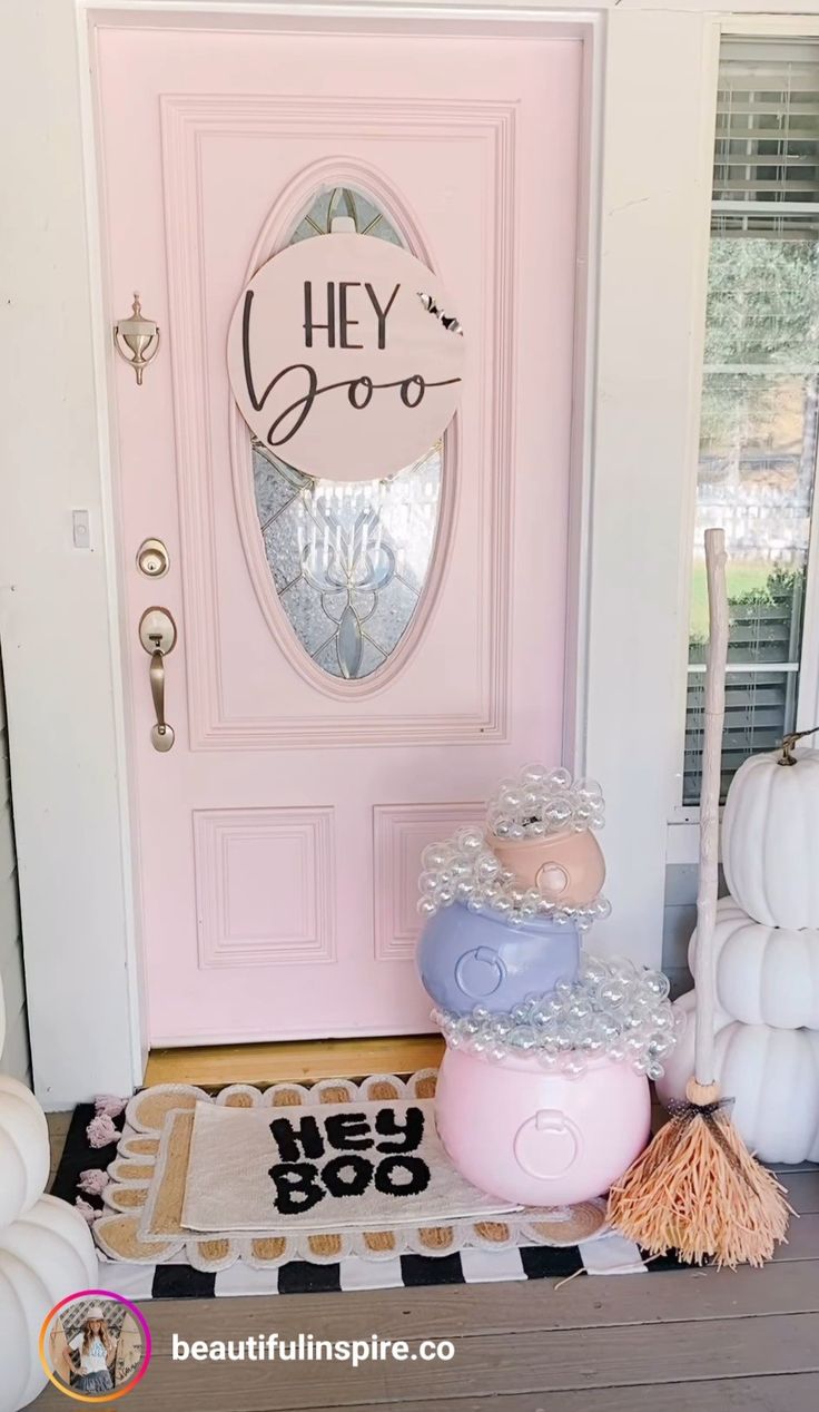 a pink door with a sign that says hey boo on it next to some decorations