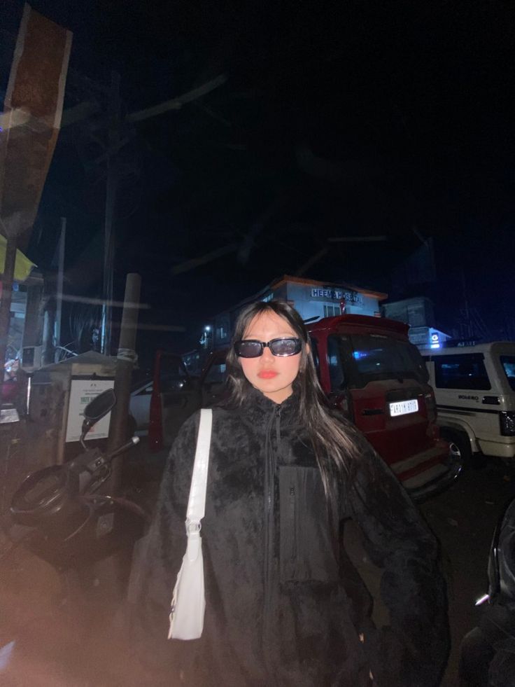 a woman wearing sunglasses walking down the street at night