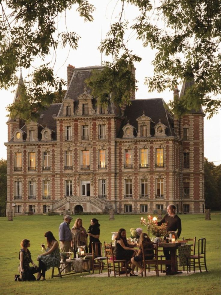 a group of people sitting around a table in front of a large building