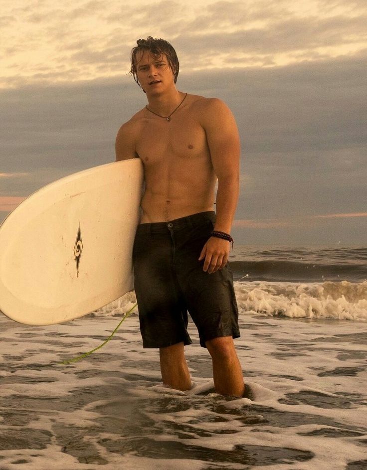 a man holding a surfboard while standing in the ocean