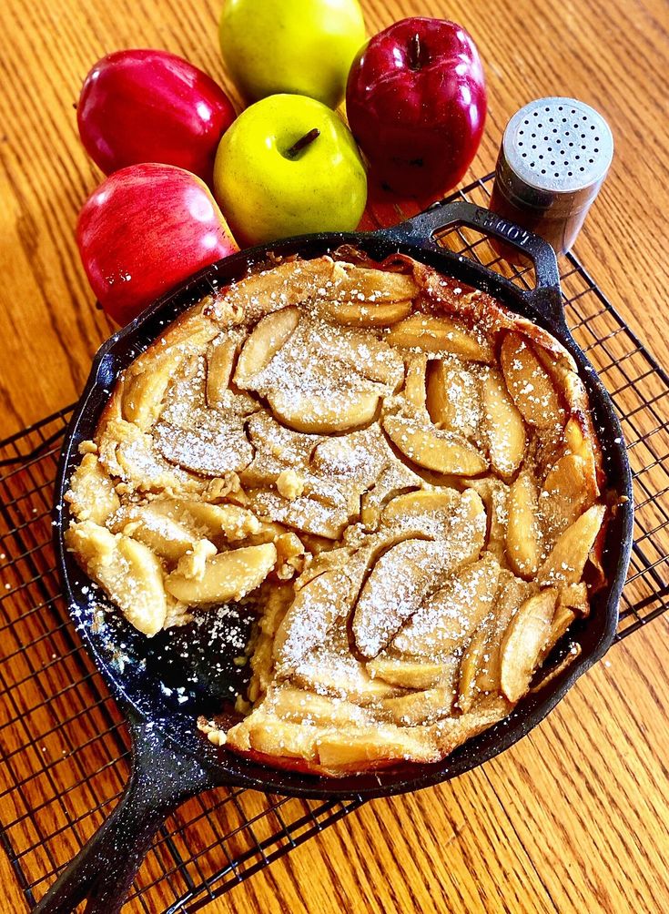 an apple pie on a cooling rack next to apples