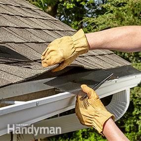 a man is working on the roof of his house with a window sealer and gloves