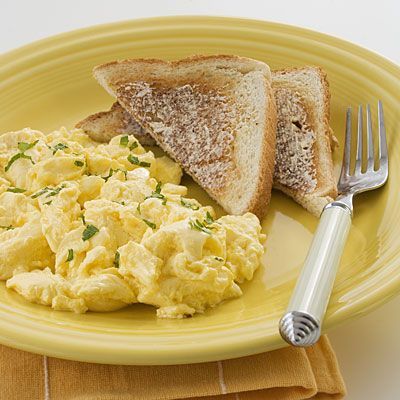 an egg salad and toast on a yellow plate with a silver fork next to it