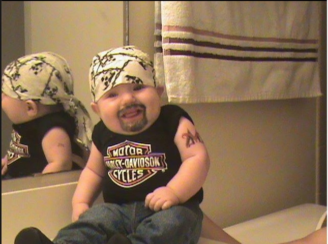 a baby sitting on top of a counter in front of a mirror wearing a bandana