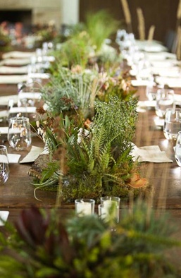 the long table is set with place settings and greenery in vases on each side