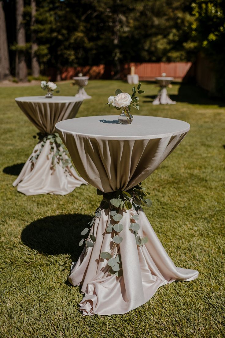 two tables covered in white cloths with flowers on them