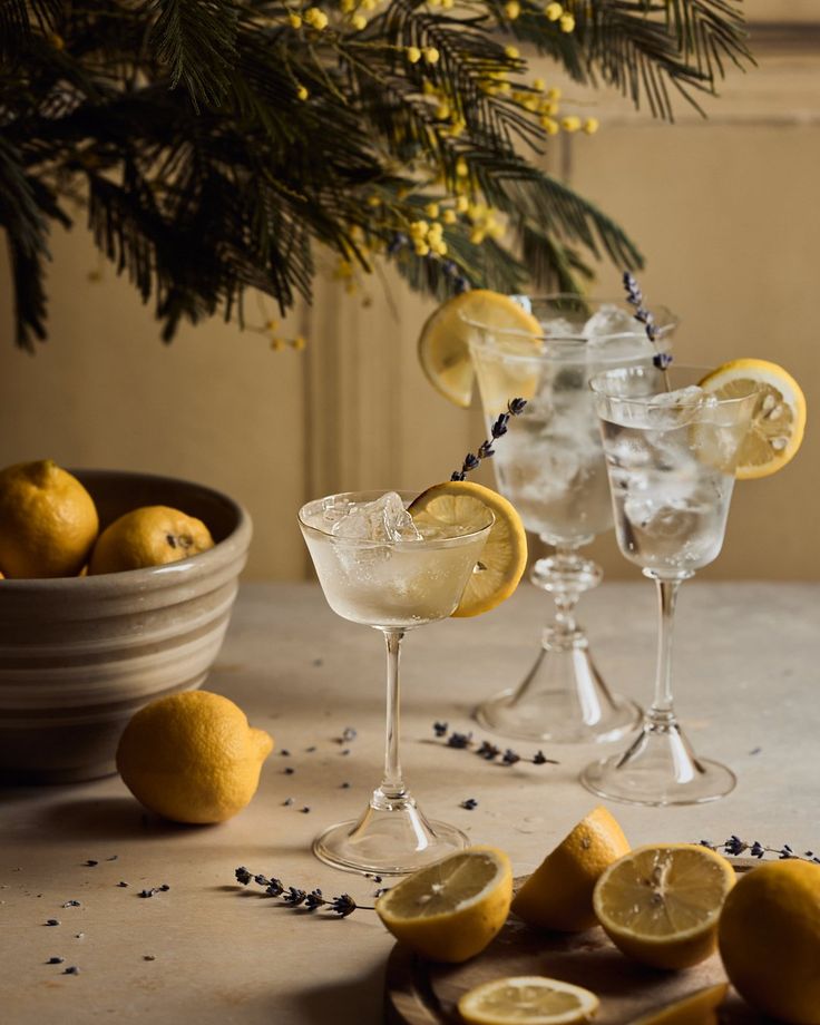 two glasses filled with lemonade sit on a table next to some sliced lemons