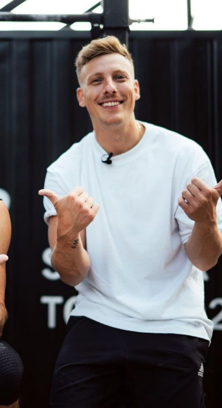 a man in white shirt and black shorts giving the peace sign