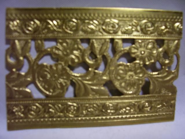 an ornate gold metal object on a white surface